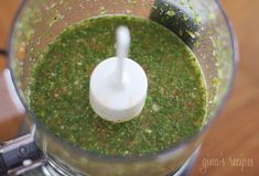 a blender filled with green liquid on top of a wooden table