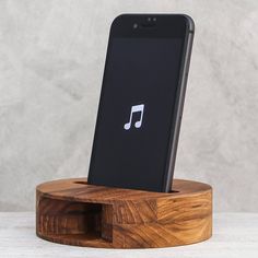 an iphone is sitting on a wooden stand with a music note in the back ground