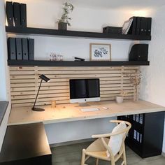 a desk with a chair, computer monitor and bookshelf above it in a room