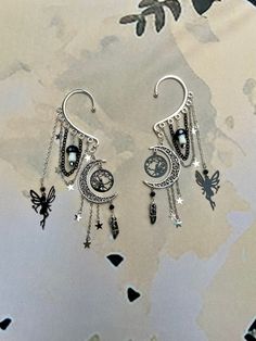 two silver earrings with charms hanging from them