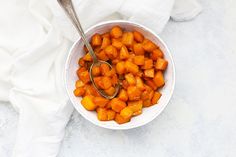 a white bowl filled with chopped up carrots and a spoon in the bowl next to it