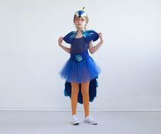 "For the kid who needs to stand out, this kid's peacock costume is lovingly handmade and totally unique. Let them flap and flutter about as a beautiful bird of paradise at their birthday, Halloween or Purim celebrations, or give the gift of dress up with this exotic ensemble. The marvelous blue felt tail is tied around the waist at the front around the tutu, and is lovingly decorated with handmade felt feathers. The felt capelet rests atop the shoulders and ties at the front, while the whole eff Flamingo Costume, Peacock Costume, Girls Costumes, Costume For Kids, Clown Costume, Halloween Costumes For Girls, Purim, Baby One Piece, Crazy Hair