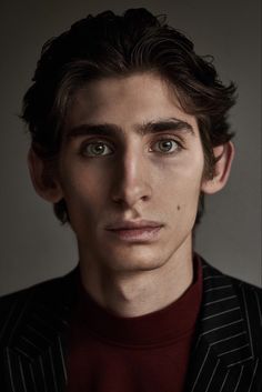 a man in a pinstripe suit looks at the camera with an intense look on his face