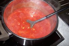 a large pot filled with red sauce on top of a stove next to an oven