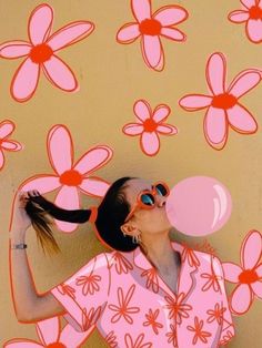 a woman blowing bubbles in front of a wall with flowers painted on it