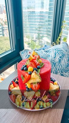 a red cake with fruit on it sitting on a table in front of a window