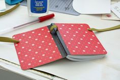 an open notebook sitting on top of a table next to some scissors and glues