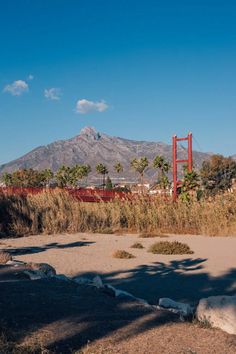 a large red structure sitting in the middle of a field with mountains in the background