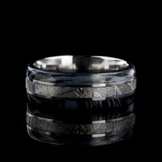 a wedding band with black and white marble inlays, set on a black background