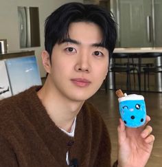 a young man holding up a cup with an ice cream inside