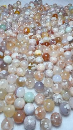 many different types of beads on a white surface with water droplets in the middle and bottom