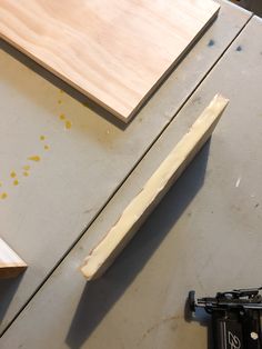 a piece of wood sitting on top of a table next to a knife and tool