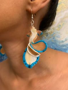 a close up of a person wearing some kind of earring with fish on it