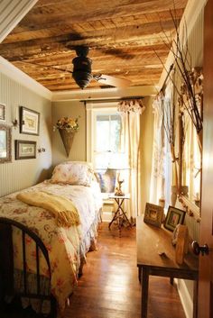 a bedroom with a bed, desk and pictures on the wall next to it's windows