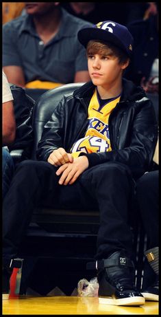 a young man sitting on top of a chair in front of a basketball game audience