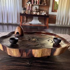 a wooden tray with two cups on it sitting on top of a table in front of a fireplace