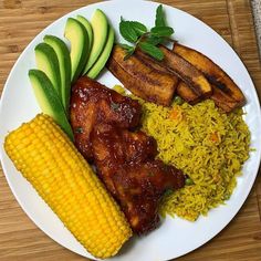 a white plate topped with meat, rice and veggies on top of a wooden table