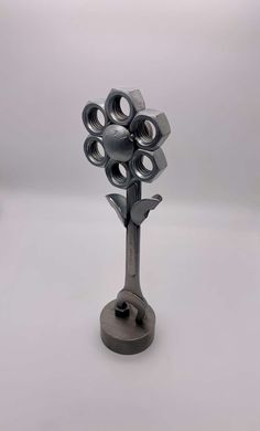 a metal sculpture with many nuts on it's head and one in the shape of a tree