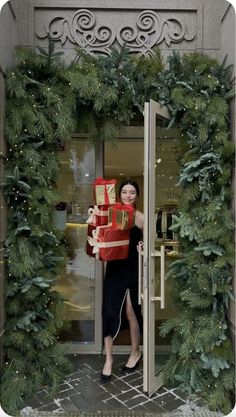 a woman standing in front of a doorway with presents wrapped in red and gold paper