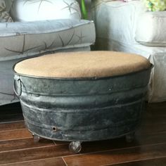 an old metal tub sitting on top of a hard wood floor next to a white couch