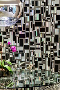 a glass table topped with a flower next to a vase filled with purple orchids