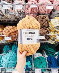 a person is holding up a yarn ball in front of some sort of basket full of yarn