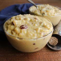 two bowls filled with oatmeal sitting on top of a wooden table next to a spoon