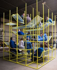 a group of people sitting on top of yellow metal shelves in a warehouse or building