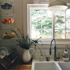 a kitchen sink sitting under a window next to a counter top with dishes on it