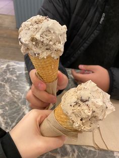 two people holding ice cream cones in their hands