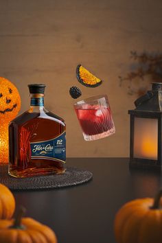 a bottle of booze sitting on top of a table next to some pumpkins