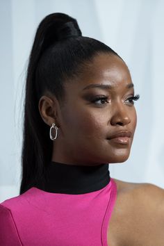 a close up of a person with a ponytail and earrings on her head, wearing a pink dress