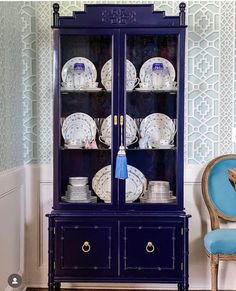 a blue china cabinet with dishes on it