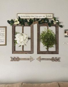 two wooden frames with flowers and arrows are hanging on the wall next to a couch