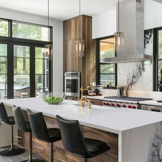 a modern kitchen with marble counter tops and black chairs in front of large windows that look out onto the backyard