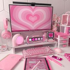 a computer desk with pink accessories and a heart - shaped wallpaper on the screen