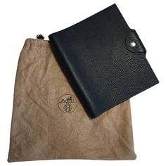 a black leather case sitting on top of a brown paper bag next to it's pouch