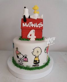 a three tiered cake decorated with snoopy and charlie the peanutshell on top