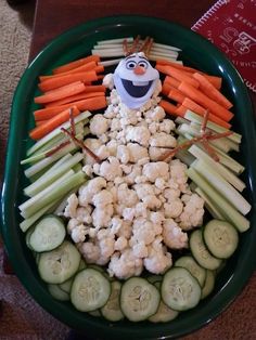 a green bowl filled with carrots, cauliflower and celery sticks