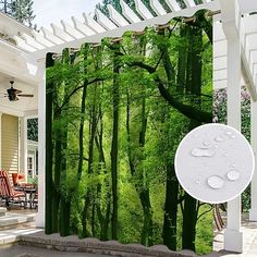 an outdoor shower curtain with green trees and water droplets on the ground in front of it