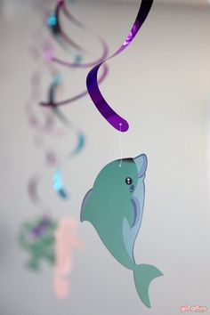 a mobile with a fish and streamers hanging from it's sides in the air