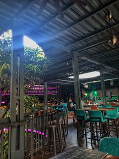 the inside of a restaurant with green chairs and plants growing on the walls, along with tables and stools