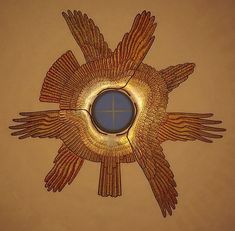 a decorative mirror mounted to the side of a wall with wings on it and a cross in the center