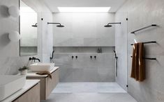 a white bathroom with two sinks, mirrors and towel racks on the wall next to it