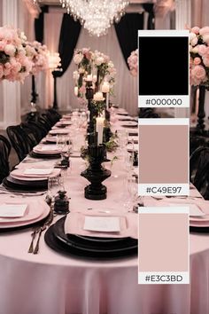 the table is set with black and white plates, silverware, pink flowers and candles