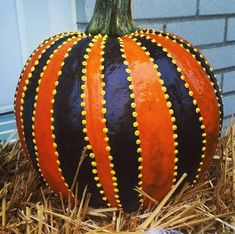 an orange and black striped pumpkin sitting on hay