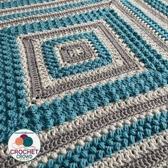 a crocheted blanket with blue and white squares on it, sitting on top of a