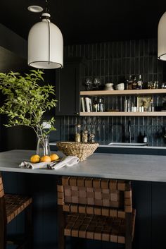 a kitchen with black cabinets and counter tops, two hanging lights above the bar area