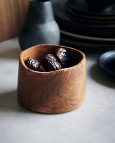 a wooden bowl filled with chocolates on top of a table next to black plates