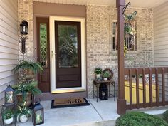 a front porch with potted plants on the steps and a doormat that says hello